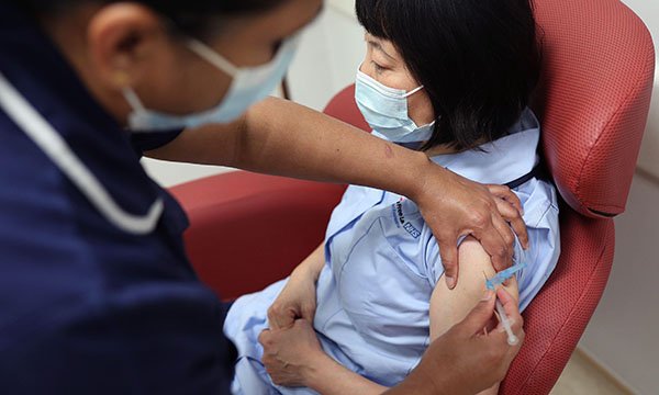 Photo of masked nurse vaccinating a colleague, the case for mandatory vaccination is being considered for nurses in England