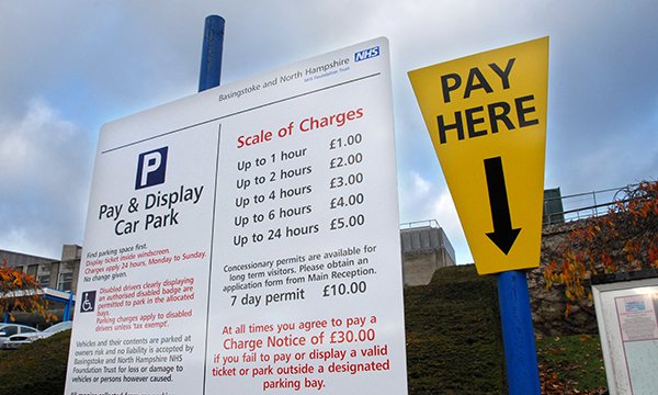 A pay and display car parking sign and meter at a hospital site