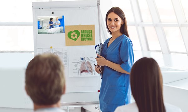 A nurse gives a presentation on sustainability in front of a flip chart