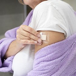 An image of a woman's arm where she is applying a HRT patch