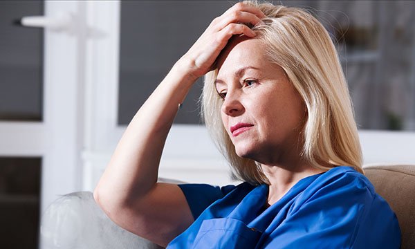 A woman experiencing perimenopause symptoms runs her fingers through her hair