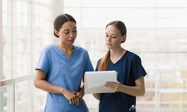 A photo of two nurses reading a report together, looking serious and concerned