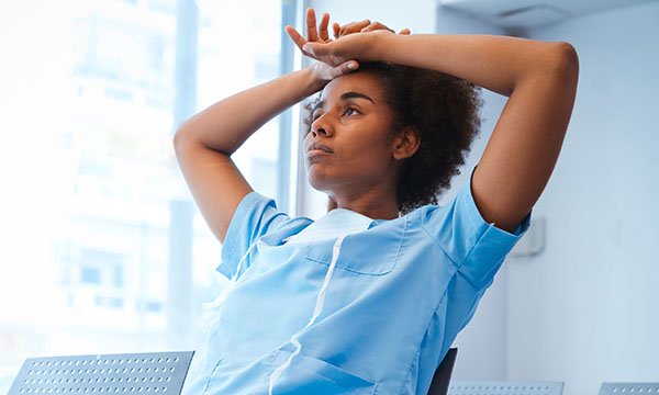A healthcare professional looking visibly tired and worried at work