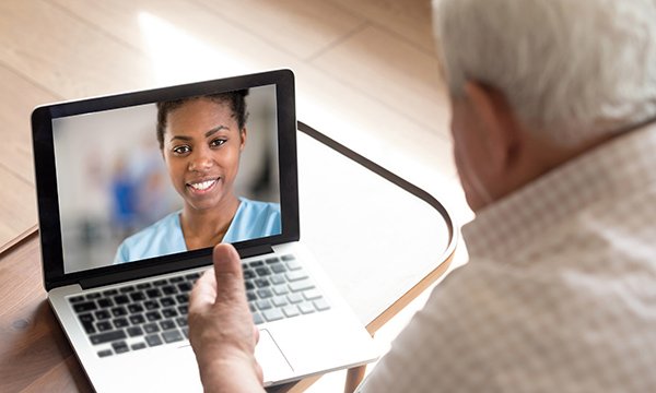 A nurse conducting a remote consultation with an older man via video call 