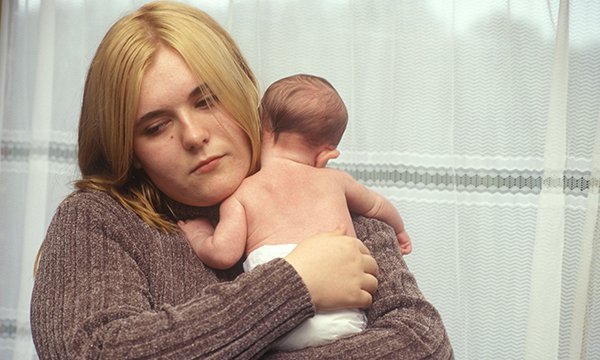 Picture show model depicting depressed young mother holding a baby. Support such as listening visits by health visitors to new mothers with mental health problems could be improved.