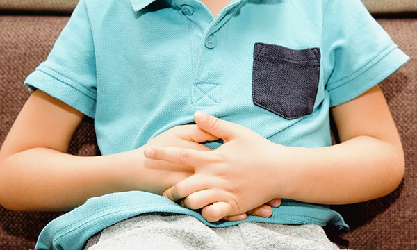 Picture shows a child with hands across their stomach as if in pain