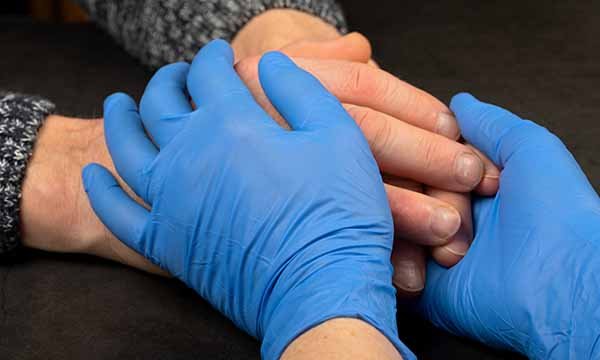 Picture shows hands clasping of two people, one wearing protective gloves.