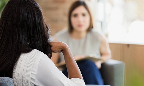 Woman listens to another, unseen, woman in counselling setting