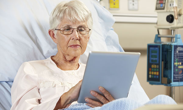 Hospital patient in bed looking at iPad
