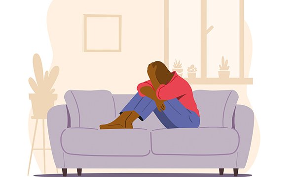 Illustration of a figure on a sofa hunched over and holding their head in a gesture of worry and anxiety; living with cancer can lead to anxiety and depression